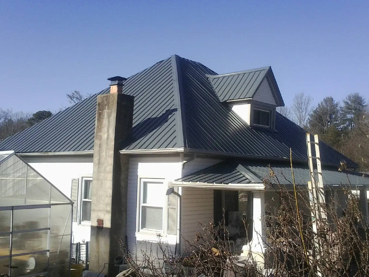 Dark blue standing seam metal roof on a white farmhouse with dormer — Slate & Tile Roof Repair by Roofing Brothers in Liberty Center