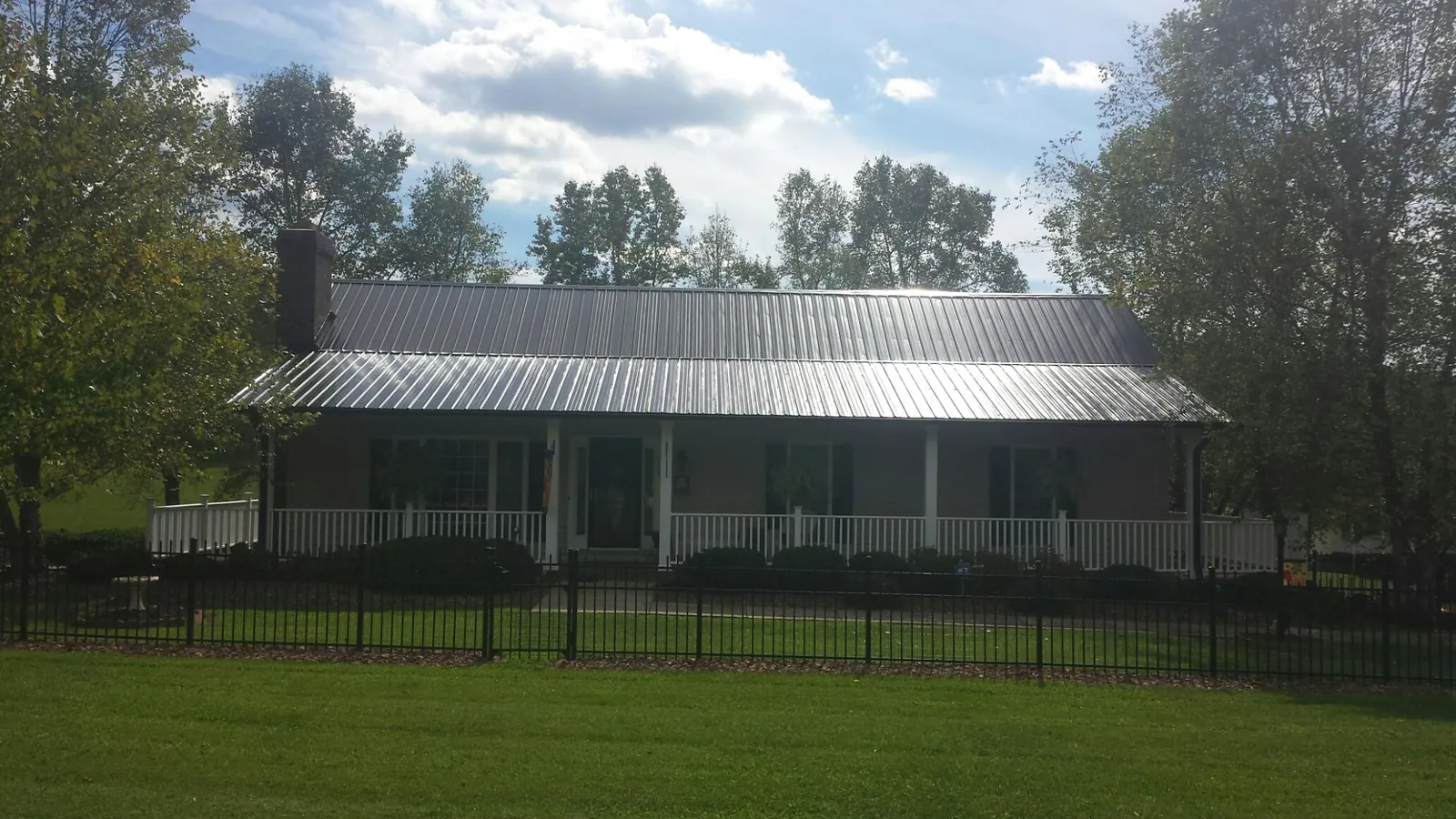 Gray metal roof on a brick ranch with a full width front porch — Gutter Guard Installation work by our crew in Liberty Center